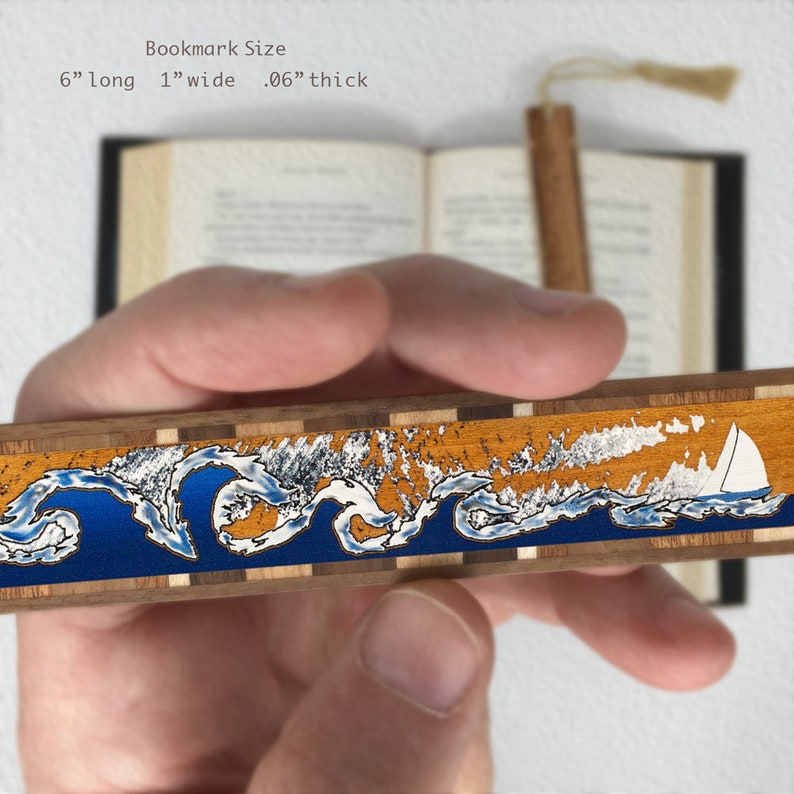 May include: Wooden bookmark featuring a blue and orange wave design with a white sailboat. The bookmark measures 6 inches long, 1 inch wide, and 0.06 inches thick.
