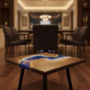 Puede incluir: Mesa de centro cuadrada de madera con incrustación de resina azul en forma de río. La mesa tiene un marco de madera oscura y patas de metal negro. La mesa mide aproximadamente 60 cm de lado y 45 cm de alto.