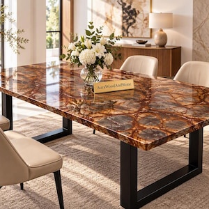 Peut inclure: Une table à manger rectangulaire avec une surface en bois pétrifié brun et ambre poli aux veines complexes, soutenue par un cadre en métal noir en forme de U. Une petite plaque dorée sur la table affiche le texte AuraWoodAndStone.