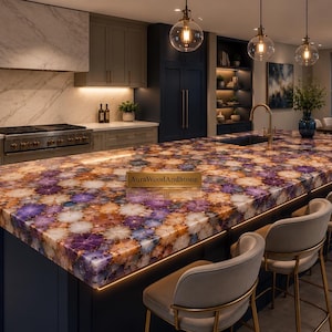 May include: A kitchen island with a multi-colored stone countertop featuring purple, orange, and white patterns. The island has a dark blue base and is surrounded by beige chairs with gold legs. Overhead, there are pendant lights.
