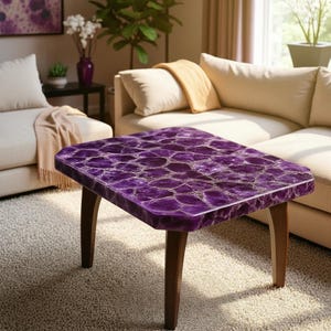 Puede incluir: Una mesa de centro rectangular con una vibrante superficie púrpura, similar a un mosaico. La mesa tiene un marco y patas de madera oscura. La mesa es un mueble único, perfecto para una sala de estar o zona de descanso.
