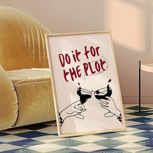 Può includere: Stampa artistica incorniciata con il testo "Do it for the Plot" in bordeaux. L'opera raffigura due mani che brindano con calici di vino, con uno stile di illustrazione in bianco e nero. La cornice è di colore legno chiaro.