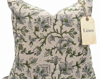 May include: A square linen cushion featuring a floral design in green and blue hues on a beige backdrop. The cushion has a tag that reads "Linen". This is a decorative item for the home.