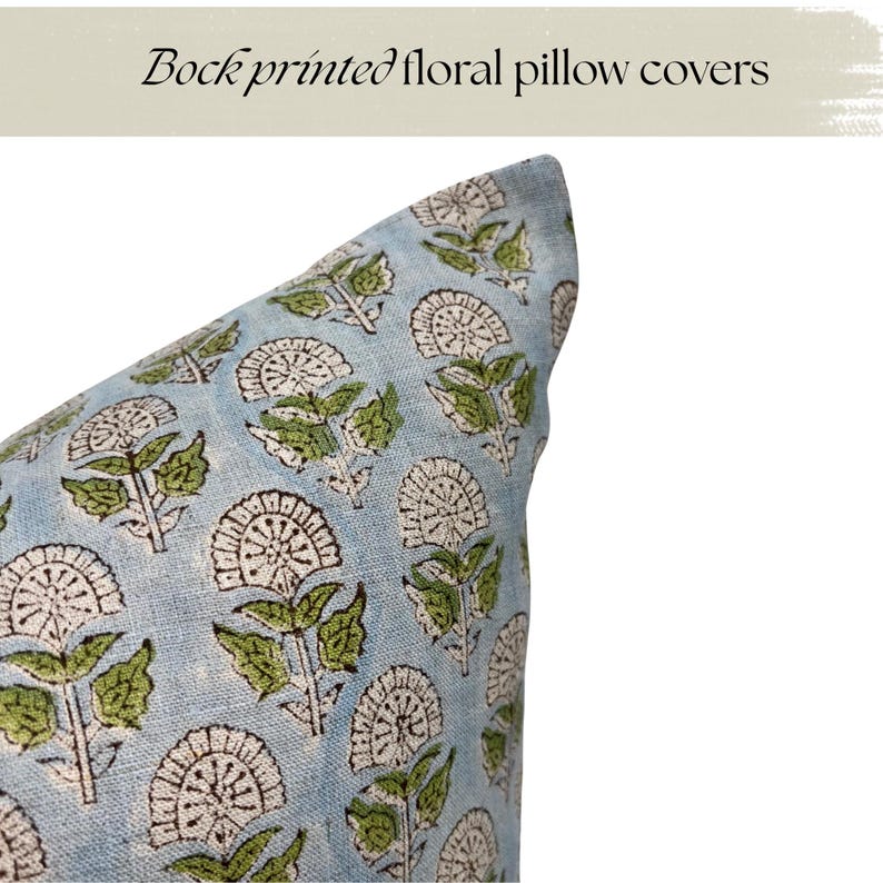 May include: Close-up of a light blue pillow cover with a repeating floral pattern. The design features white and brown flower shapes with green leaves. The text "Block printed floral pillow covers" is at the top.