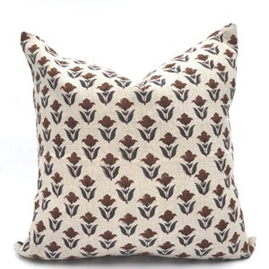 Puede incluir: Una funda de cojín con estampado floral marrón y blanco. La funda de cojín tiene un patrón repetitivo de flores marrones con tallos marrones oscuros sobre un fondo blanco.
