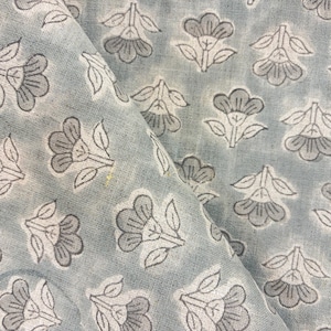 May include: A light blue fabric featuring a repeating pattern of dark gray hand-stamped flowers with leaves. The textile has a visible woven texture and a soft, muted color palette with consistent floral motifs arranged in a grid-like layout.