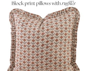 Könnte beinhalten: Ein quadratisches Kissen mit einem floralen Blockdruck-Design in Rost-, Grau- und Cremetönen. Das Kissen hat einen gerüschten Rand und der Text "Block print pillows with ruffles" wird oben angezeigt.