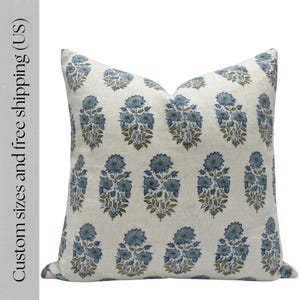 Peut inclure: Coussin carré avec un motif floral répétitif bleu et vert olive sur fond crème. Le coussin a un aspect texturé, probablement en lin ou dans un tissu similaire. Un article de décoration intérieure.