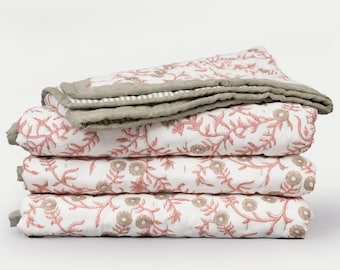May include: A stack of four white quilts with a floral pattern in shades of pink and brown. The quilts are folded and stacked on top of each other. The edges are trimmed with a gray border.