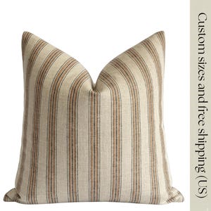 May include: A square pillow with a cream-colored background and vertical stripes in shades of brown and black. The pillow has a soft, textured appearance. The text on the side reads "Custom sizes and free shipping (US)".