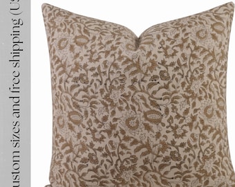 Puede incluir: Cojín cuadrado con fondo beige y un patrón floral repetido en tonos marrones. El cojín tiene un aspecto suave y acogedor, adecuado para la decoración del hogar.