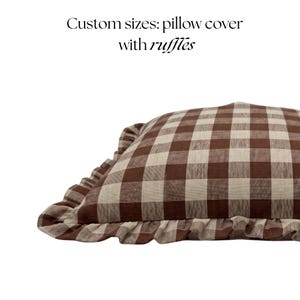 K&ouml;nnte beinhalten: Eine braun-beige karierte Kissenh&uuml;lle mit R&uuml;schenkanten. Das Kissen hat ein klassisches Vichy-Muster und wird vor einem wei&szlig;en Hintergrund gezeigt. Der Text auf dem Bild lautet: "Custom sizes: pillow cover with ruffles."