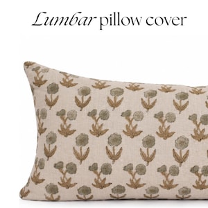 Puede incluir: Una funda de cojín lumbar rectangular de tela beige claro con un patrón floral bordado repetitivo en verde salvia apagado y marrón claro. El texto "Lumbar pillow cover" está impreso en negro sobre la funda en un fondo blanco.