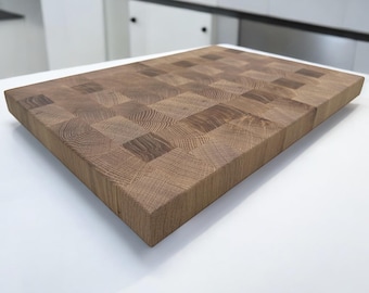 May include: A large, rectangular wooden chopping board with a chequered pattern. The board is made of light and dark wood, creating a contrasting effect. The board is made of solid wood and is designed for durability.