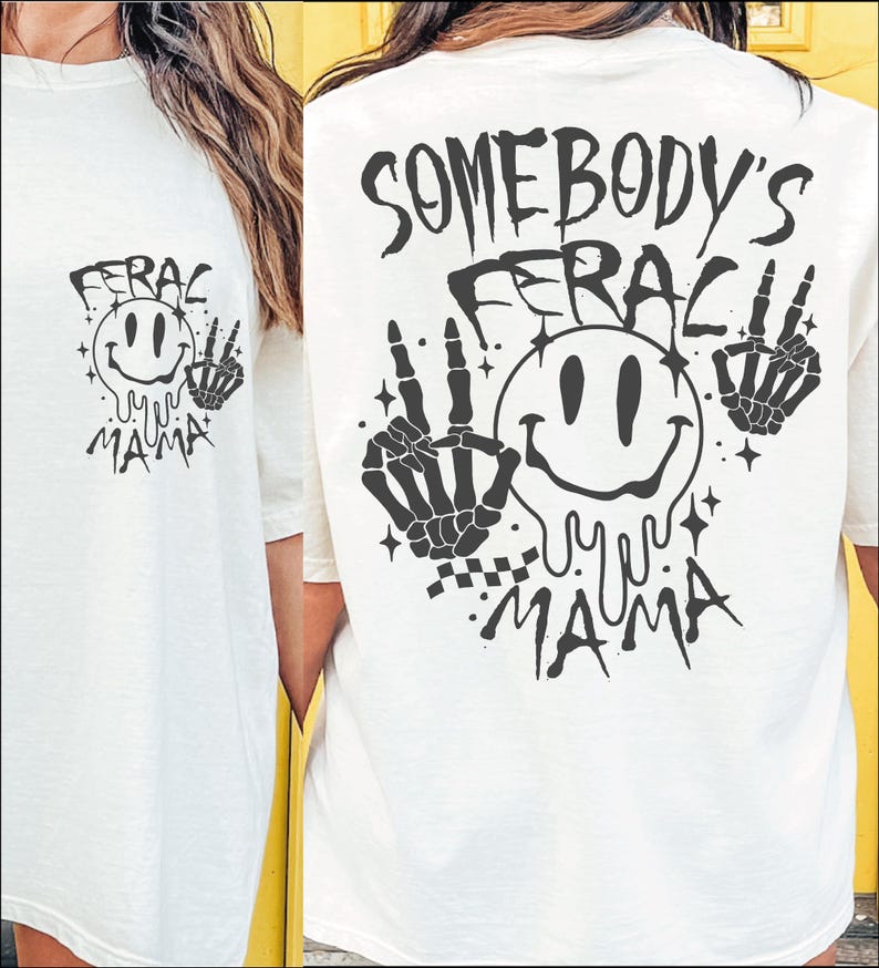 May include: White t-shirt with a black graphic print of a smiley face with dripping eyes and the text "Somebody's Feral Mama" on the back. The graphic also includes two skeleton hands with peace signs.