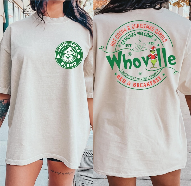 Peut inclure: Un t-shirt blanc avec un logo vert Grinchmas Blend sur le devant et un logo vert Whoville au dos. Le logo Whoville comprend le texte "Hot Cocoa & Christmas Carols", "Grinches Welcome", "Est. 1954", "Located next to Mount Crumpit", et "Bed & Breakfast".