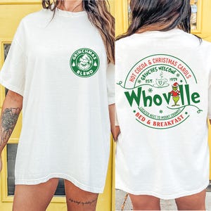 Peut inclure: T-shirt blanc avec un logo vert Grinchmas Blend sur le devant et un logo vert Whoville au dos. Le logo Whoville comprend le texte "Hot Cocoa & Christmas Carols", "Grinches Welcome", "Est. 1954", "Located next to Mount Crumpit", et "Bed & Breakfast".