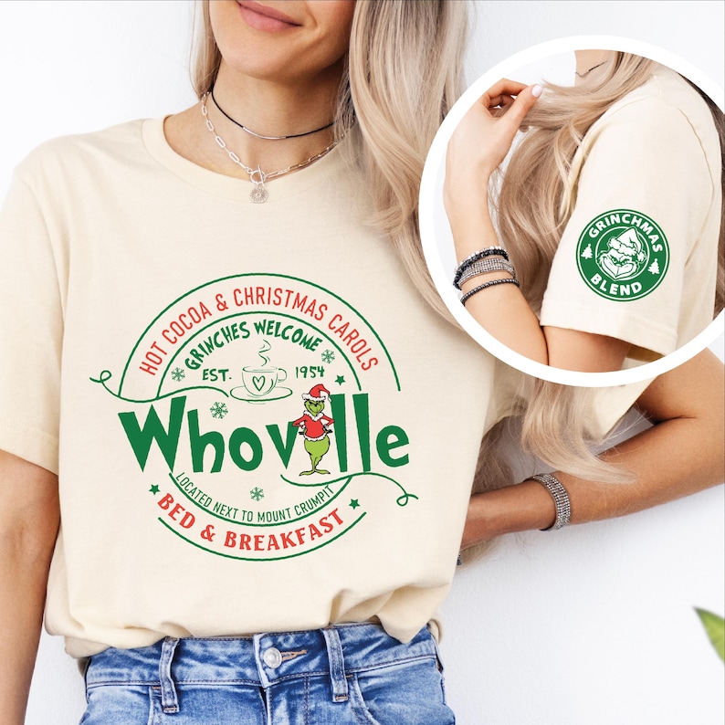 Peut inclure: Un t-shirt cr&egrave;me avec un motif vert et rouge qui dit "Hot Cocoa & Christmas Carols *Grinches Welcome* Est. 1954 Whoville *Located next to Mount Crumpit* Bed & Breakfast" avec un personnage de dessin anim&eacute; du Grinch. La manche droite a un cercle vert avec le texte "Grinchmas Blend" et un personnage de dessin anim&eacute; du Grinch.