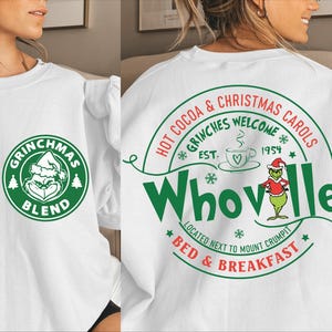 Peut inclure: Sweat-shirt blanc avec un imprim&eacute; graphique vert et rouge sur le th&egrave;me de No&euml;l du Grinch. Le motif comprend le texte "Grinchmas Blend", "Hot Cocoa & Christmas Carols", "Grinches Welcome", "Est. 1954", "Whoville", "Located next to Mount Crumpit", et "Bed & Breakfast".
