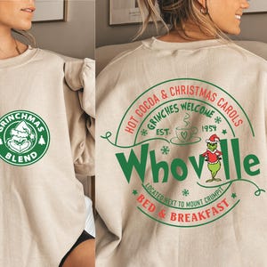 Peut inclure: Un sweat-shirt beige avec un logo Grinchmas Blend vert et blanc sur le devant et un logo Whoville vert et rouge au dos. Le logo Whoville comprend le texte "Hot Cocoa & Christmas Carols", "Grinches Welcome", "Est. 1954", et "Bed & Breakfast".
