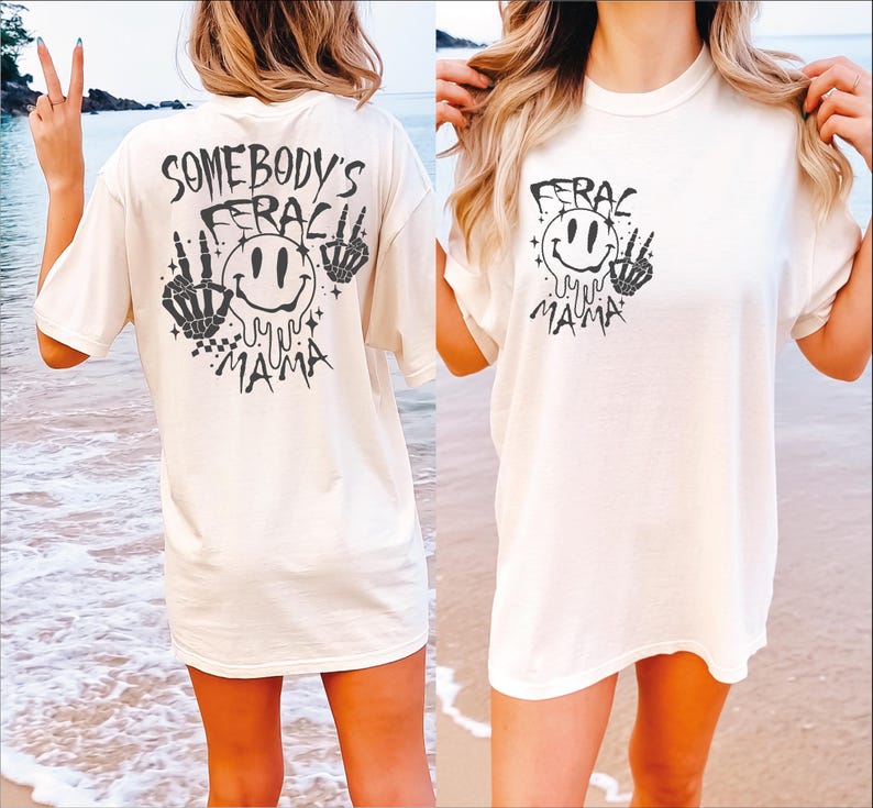 May include: White oversized t-shirt with a black graphic print of a smiley face with the text "Somebody's Ferac Mama" on the back and "Ferac Mama" on the front.