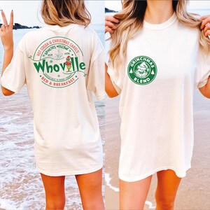 Peut inclure: T-shirt blanc avec un imprim&eacute; graphique vert et blanc du Grinch sur le devant et un imprim&eacute; graphique vert et blanc du Grinch au dos. Le texte au dos est "Hot Cocoa & Christmas Carols, Grinches Welcome, Est. 1959, Whoville, Located Next to Mount Crumpit, Bed & Breakfast". Le texte sur le devant est "Grinchmas Blend".
