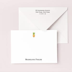Könnte beinhalten: Weißes Briefpapier-Set mit einer Ananas-Illustration. Das Set enthält eine gefaltete Karte mit dem Namen "Madeline Fields" und einen Umschlag mit einer aufgedruckten Adresse. Die Adresse lautet "123 Anywhere Avenue, New York, New York 10016".