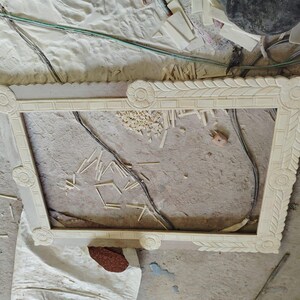 May include: A rectangular, light-colored wooden picture frame featuring intricate carved floral motifs at each corner and a repeating leaf pattern along the inner border, showcasing detailed craftsmanship and a natural, unfinished wood texture.