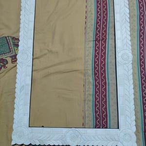 May include: A rectangular white picture frame featuring intricate carved floral motifs at each corner and along the center of each side. The frame border is decorated with a repeating leaf pattern and smooth rectangular segments.