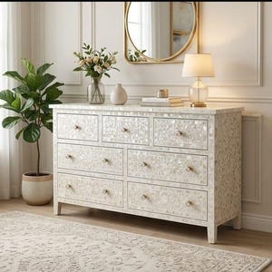May include: A rectangular dresser featuring an intricate white mother-of-pearl inlay pattern across its seven drawers. Each drawer is equipped with a small, round, metallic knob. The piece stands on four short, straight legs and has a smooth top surface.