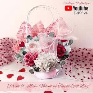 Puede incluir: Una bolsa de regalo con forma de tetera con temática de San Valentín, llena de flores de papel y papel de seda. La bolsa es blanca con un asa, y las flores son rosas y rojas. El texto "Print & Make: Valentine Teapot Gift Bag" está en la parte inferior.