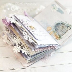 May include: A white and purple journal with lace trim and a floral design. The journal is open to reveal a page with the text "Heart & Home" written in cursive.