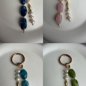 Puede incluir: Cuatro llaveros con cierres dorados. Cada llavero presenta un dise&ntilde;o diferente: cuentas de piedras preciosas azules, rosas, turquesas y verdes, combinadas con perlas blancas. Los llaveros se muestran sobre una superficie blanca.