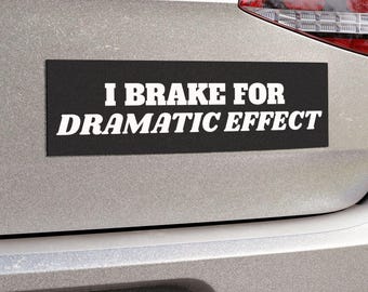 May include: A black and white bumper sticker on a silver car that reads "I Brake For Dramatic Effect."