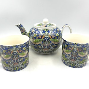 May include: A blue and green teapot and two mugs with a floral pattern. The teapot has a white lid and a handle. The mugs have white handles.