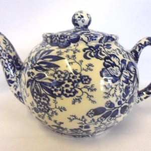 May include: A blue and white floral patterned teapot with a lid. The teapot is made of ceramic and has a classic design.