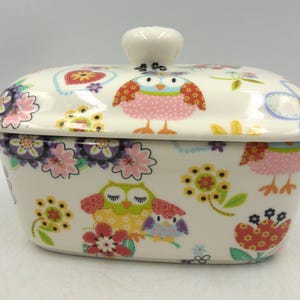 May include: White ceramic butter dish with a lid. The dish is decorated with a colourful floral pattern and owls. The lid has a knob in the shape of an owl.