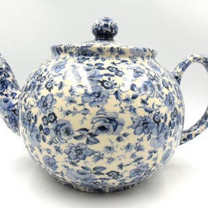 May include: A blue and white floral teapot with a round body and a lid. The teapot has a spout and a handle.