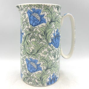 以下が含まれることがあります： 青と緑の花柄が描かれた白い陶器のピッチャー。ピッチャーは口が広く、持ち手があります。