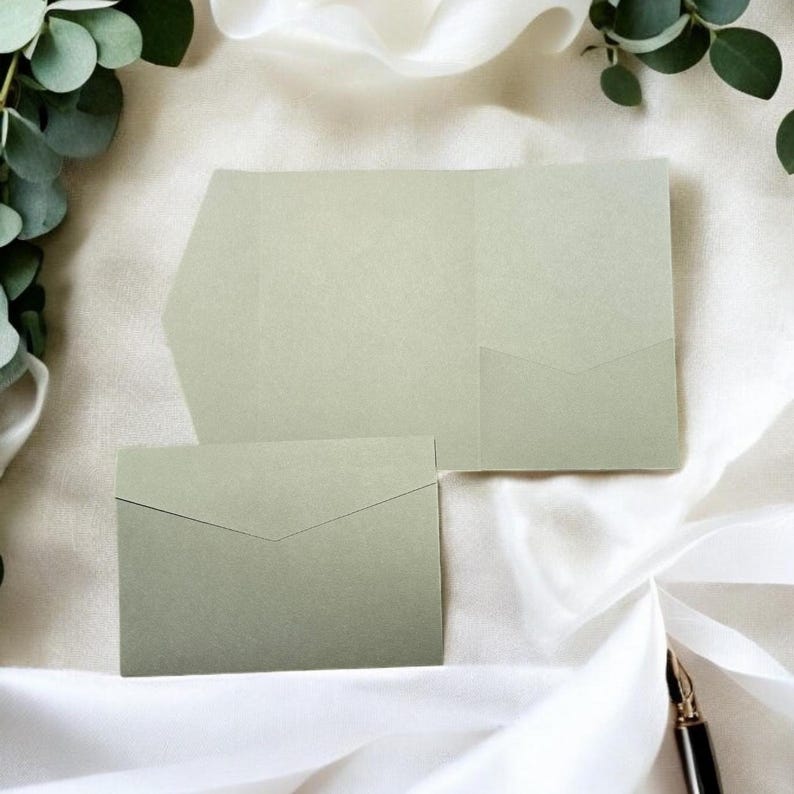 May include: A set of two sage green envelopes, one with a pocket for a card or invitation. The envelopes are made of a textured paper.