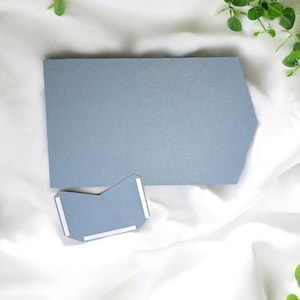 May include: A light blue card with a slightly pointed edge. The card is blank and has a smaller, similarly shaped card attached to it with adhesive.