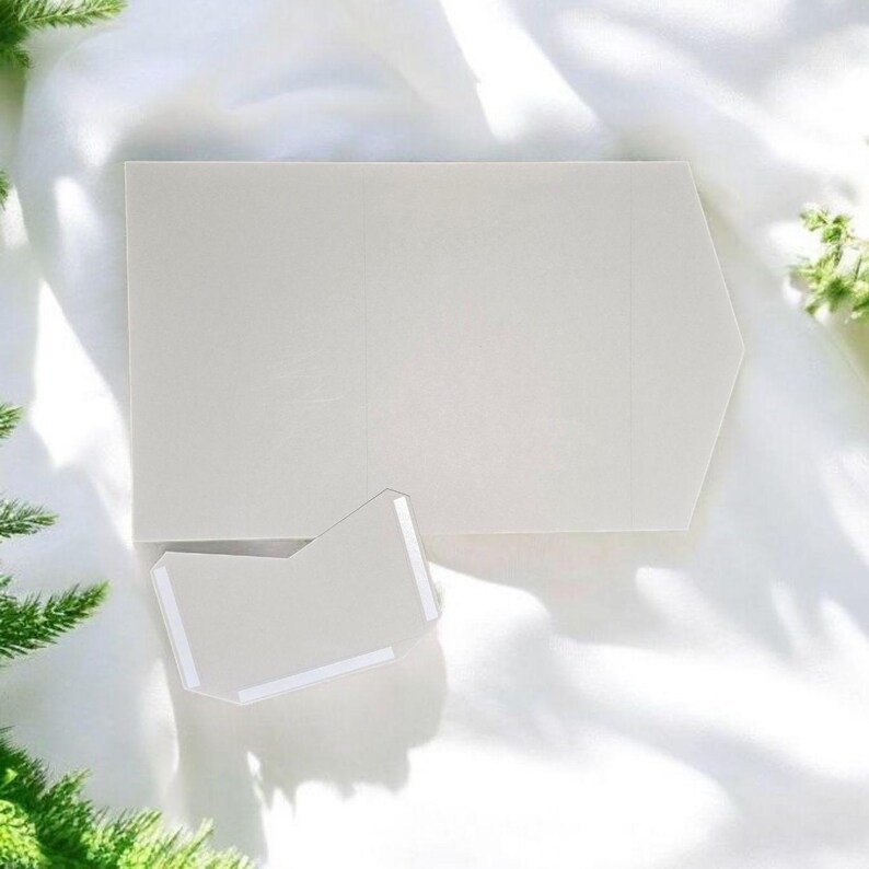 May include: A white card with a folded flap, creating a pocket shape. The card is on a white surface.
