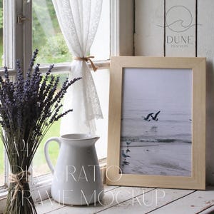 Puede incluir: Un marco de madera clara con una impresión de una escena costera con gaviotas en vuelo. Una jarra blanca y un ramo de lavanda están en el alféizar de la ventana. El texto "A4 DIY Ratio Frame Mockup" es visible.