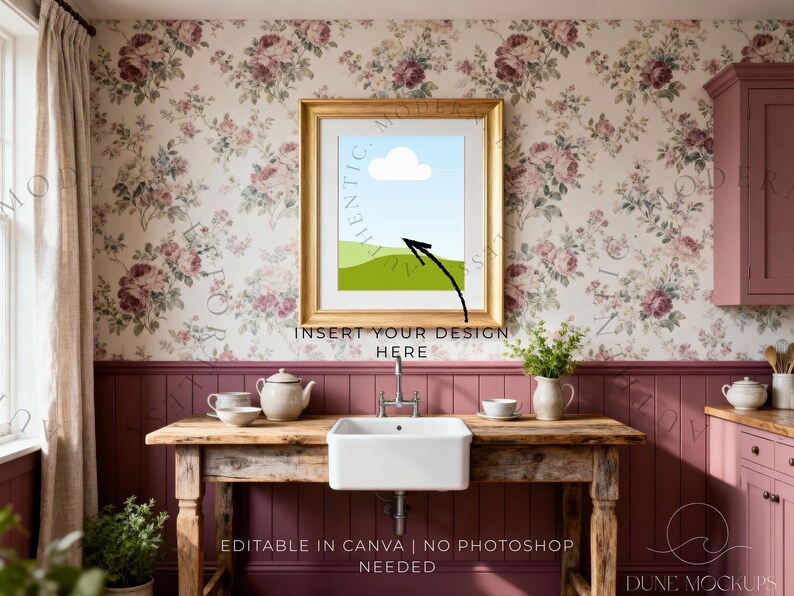 May include: A framed art print mockup with a gold frame, featuring a landscape design with a blue sky, white cloud, and green hills. The image is set in a kitchen with floral wallpaper and a wooden table with a sink.