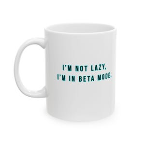 Puede incluir: Taza de cerámica blanca con asa curva. La taza presenta el texto "I'M NOT LAZY, I'M IN BETA MODE" en color turquesa, con fuente sans-serif. La taza está diseñada para bebidas frías o calientes.