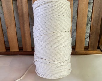 Puede incluir: Un rollo de cuerda de algodón blanco natural, enrollado firmemente y listo para ser utilizado en proyectos de manualidades o macramé.