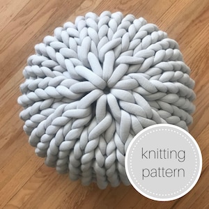 May include: A large, round, gray knitted ottoman with a chunky knit pattern. The ottoman is made with thick yarn and has a soft, plush texture. The text "knitting pattern" is visible in the lower right corner of the image.