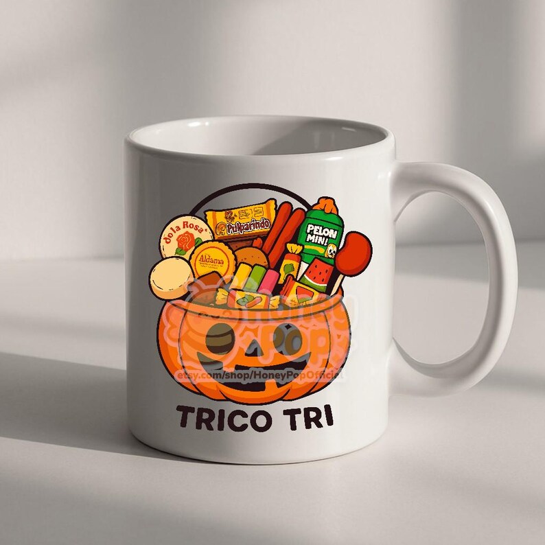 Peut inclure: Mug en c&eacute;ramique blanche avec un dessin de citrouille de dessin anim&eacute; remplie de bonbons et de collations. La citrouille a un visage souriant et est remplie de diverses friandises. Le mug porte l'inscription "TRICO TRI" en bas.