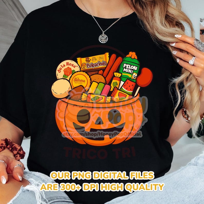 Peut inclure: T-shirt noir avec un motif d'Halloween. Il repr&eacute;sente une citrouille sculpt&eacute;e remplie de bonbons et de collations. Le texte "TRICO TRI" et "OUR PNG DIGITAL FILES ARE 300+ DPI HIGH QUALITY" sont &eacute;galement visibles. Le t-shirt a un col rond.