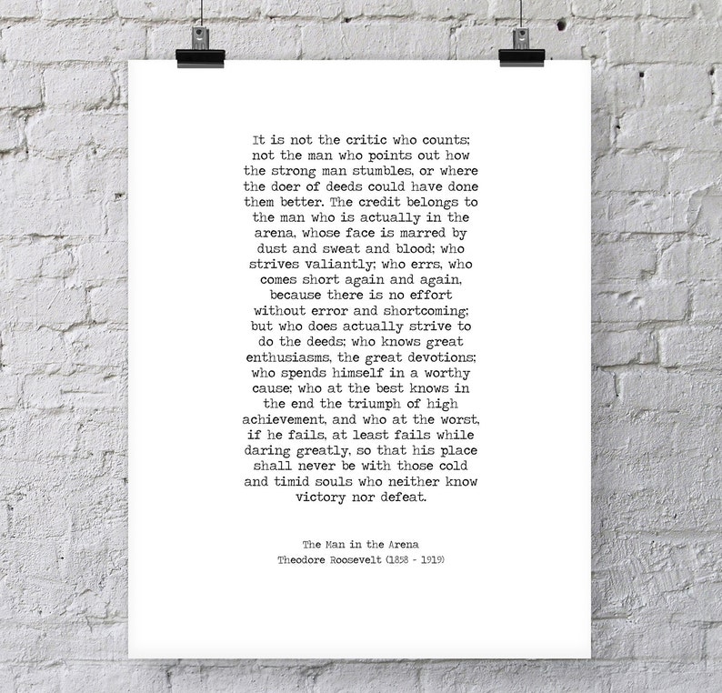 May include: Black and white typography print with a quote by Theodore Roosevelt about the importance of action and perseverance. The quote reads, "It is not the critic who counts; not the man who points out how the strong man stumbles, or where the doer of deeds could have done them better. The credit belongs to the man who is actually in the arena, whose face is marred by dust and sweat and blood; who strives valiantly; who errs, who comes short again and again, because there is no effort without error and shortcoming: but who does actually strive to do the deeds; who knows great enthusiasms, the great devotions; who spends himself in a worthy cause; who at the best knows in the end the triumph of high achievement, and who at the worst, if he fails, at least fails while daring greatly, so that his place shall never be with those cold and timid souls who neither know victory nor defeat." The quote is attributed to Theodore Roosevelt (1858-1919) and is titled "The Man in the Arena."